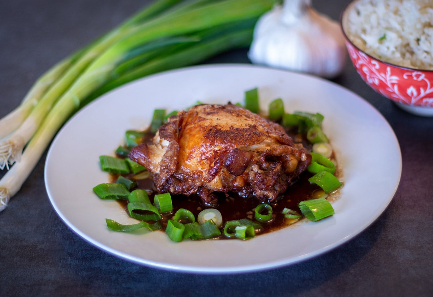 Instant Pot Crispy Chicken Adobo on a white plate with scallions, garlic and white rice