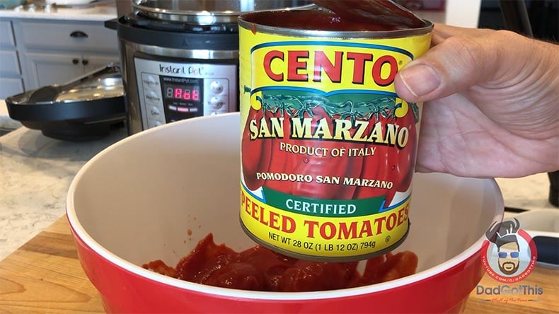 A can of San Marzano Peeled Plum Tomatoes over a working bowl with an instant pot in the background.