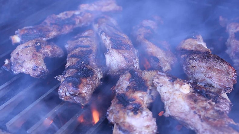 Ribs smoking on a grill with flames