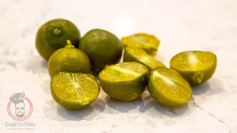 Whole and cut Calamansi or Philippine limes on a counter.
