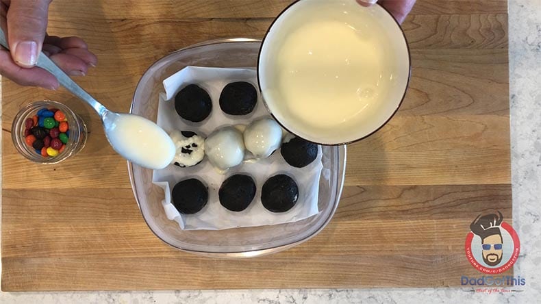 a spoon pouring icing over oreo truffles