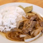 Instant Pot Pork Bistek Tagalog on a white plate with a side of white rice.