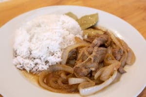 Instant Pot Pork Bistek Tagalog on a white plate with a side of white rice.