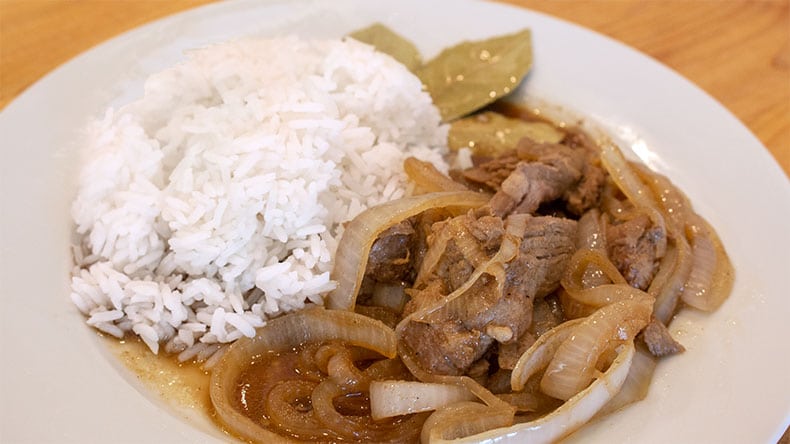 pork bistek tagalog on a white plate with white rice