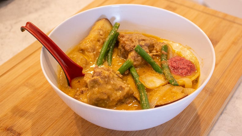 A bowl on instant pot kare kare with a red spoon