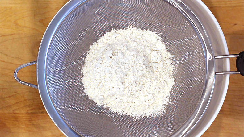 flour in a sifter over a bowl