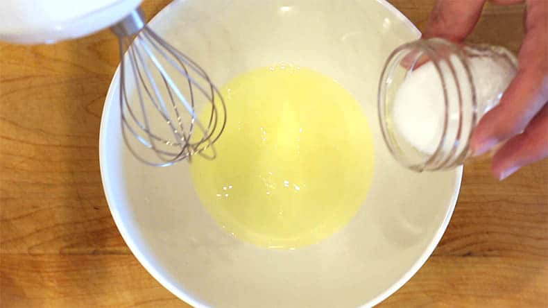 egg whites in a bowl with a mixer above it