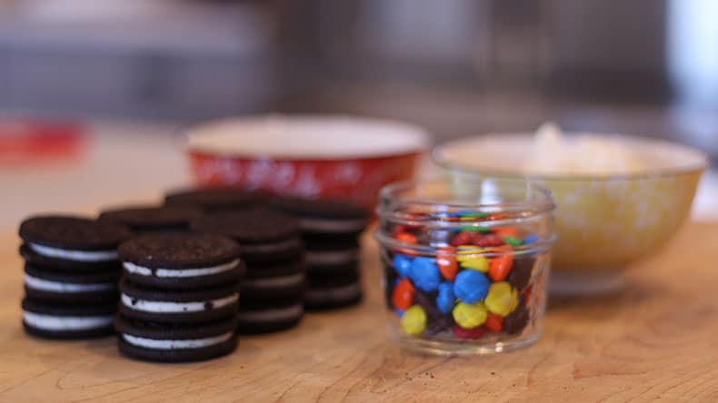 oreo cookies, mm candies and bowls on a cutting board