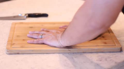 hands pressing down on a cutting board