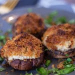 3 crab stuffed mushrooms on a grey plate