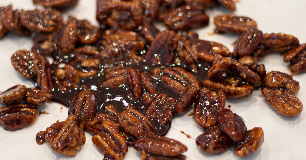 Candied pecans cooling on a piece of wax paper