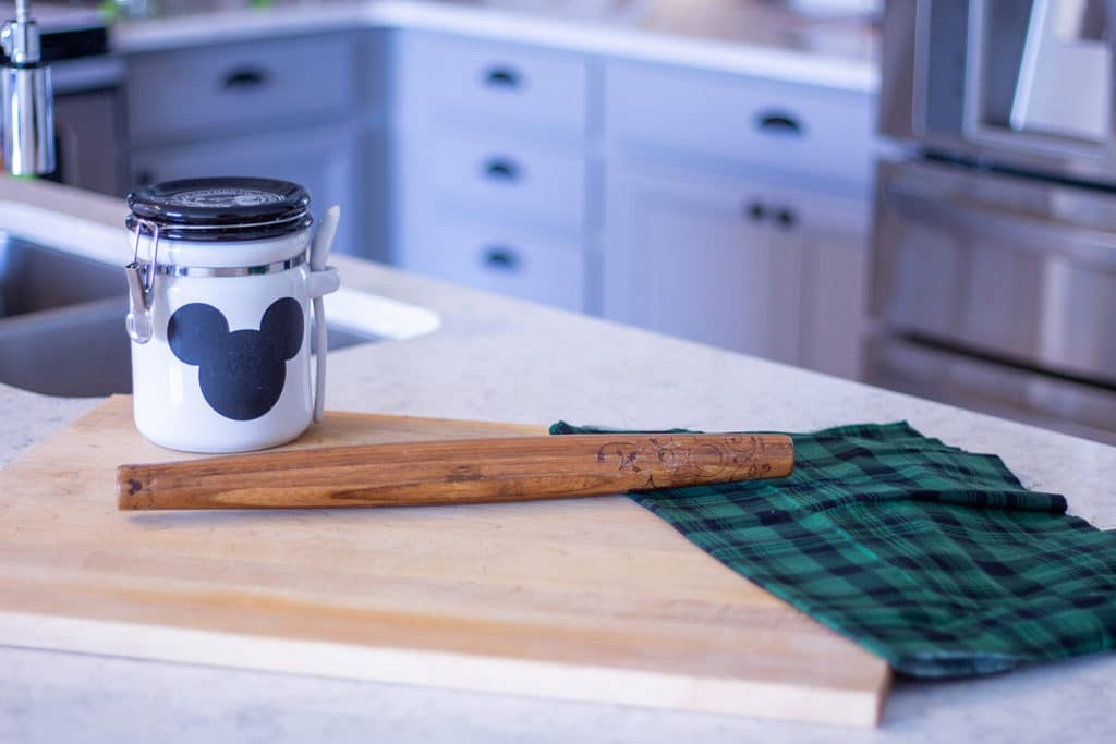 a large wood cutting board on a counter with a jar and a rolling pin