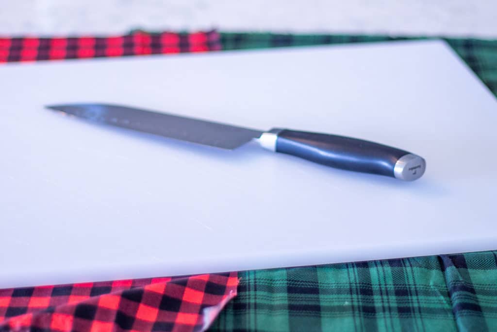 a white cutting board with a knife on it