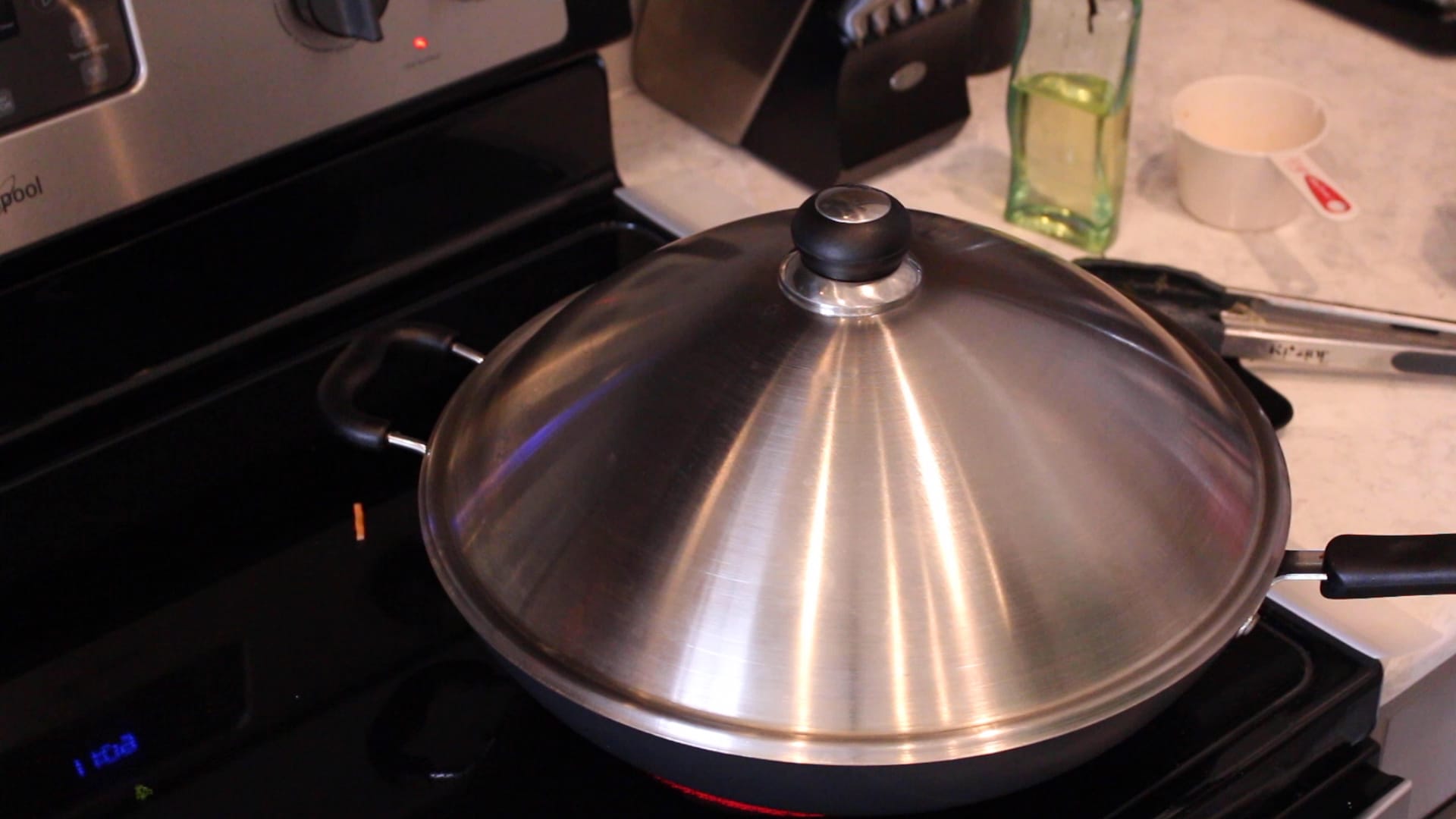 A wok with a lid on a stove.
