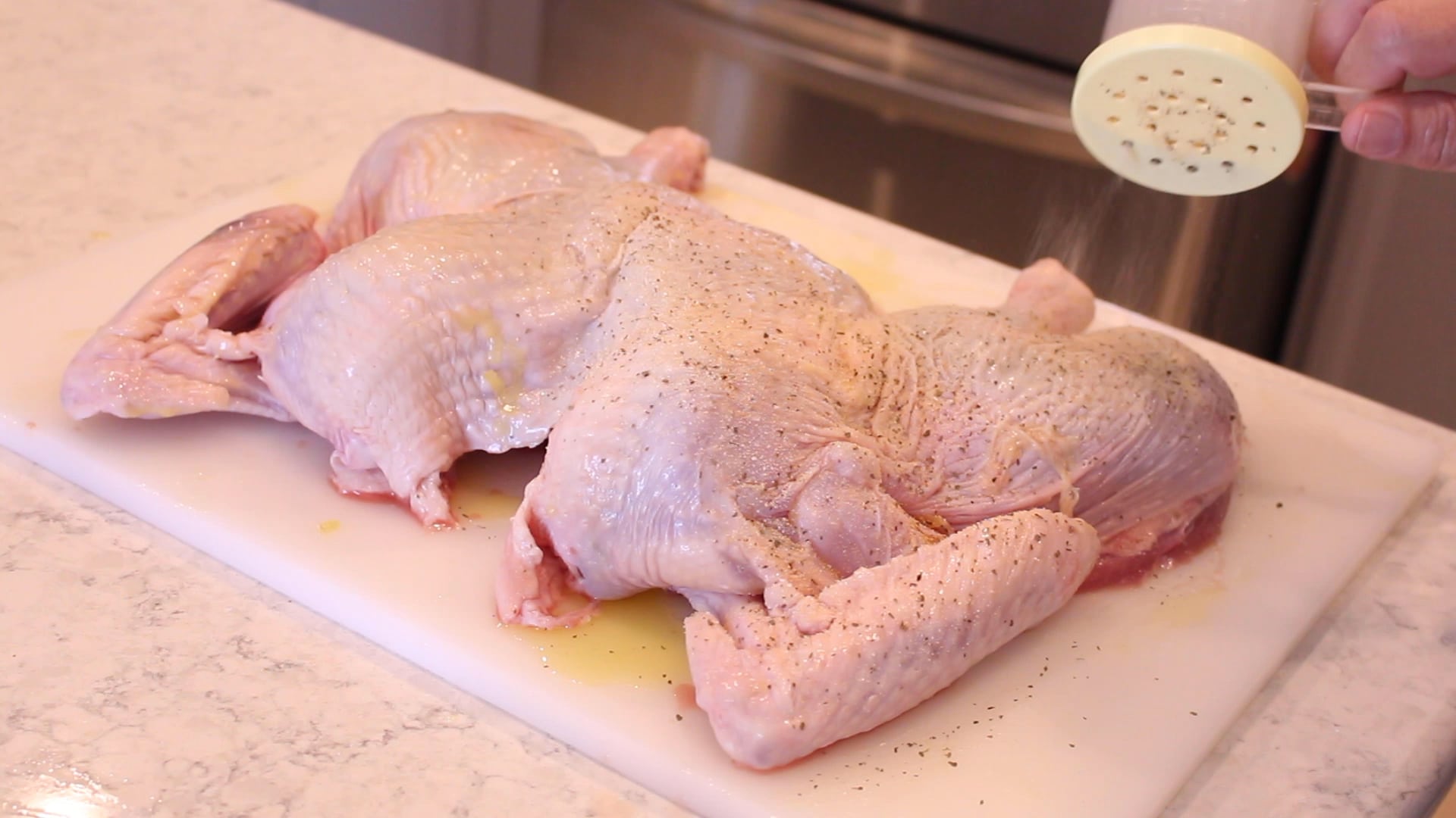 sprinkling spices on a spatchcocked turkey