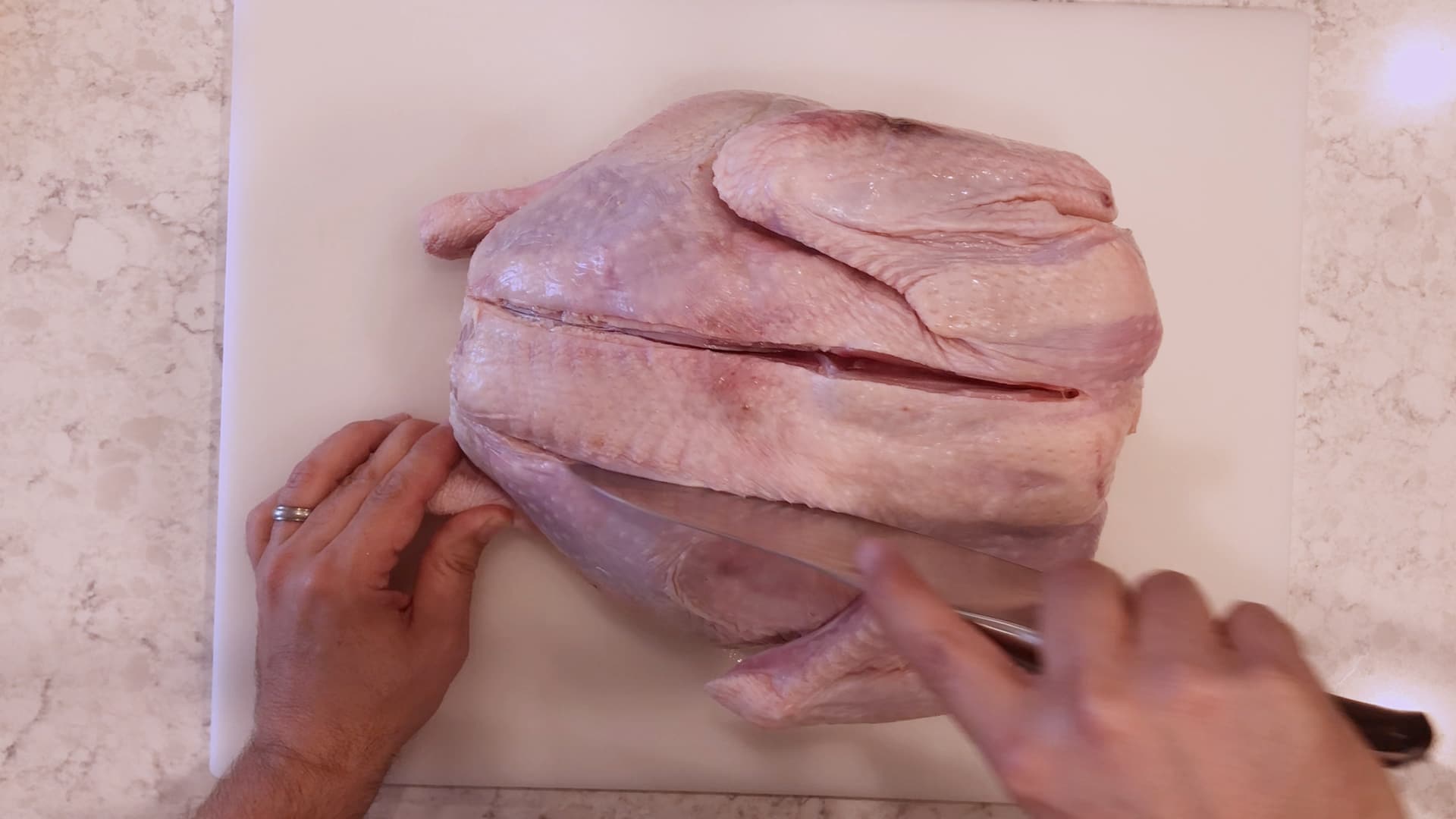 A turkey on a cutting board with two slices along the backboard