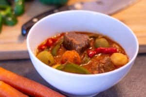 Instant Pot Beef Kaldereta in a bowl on a counter with carrots