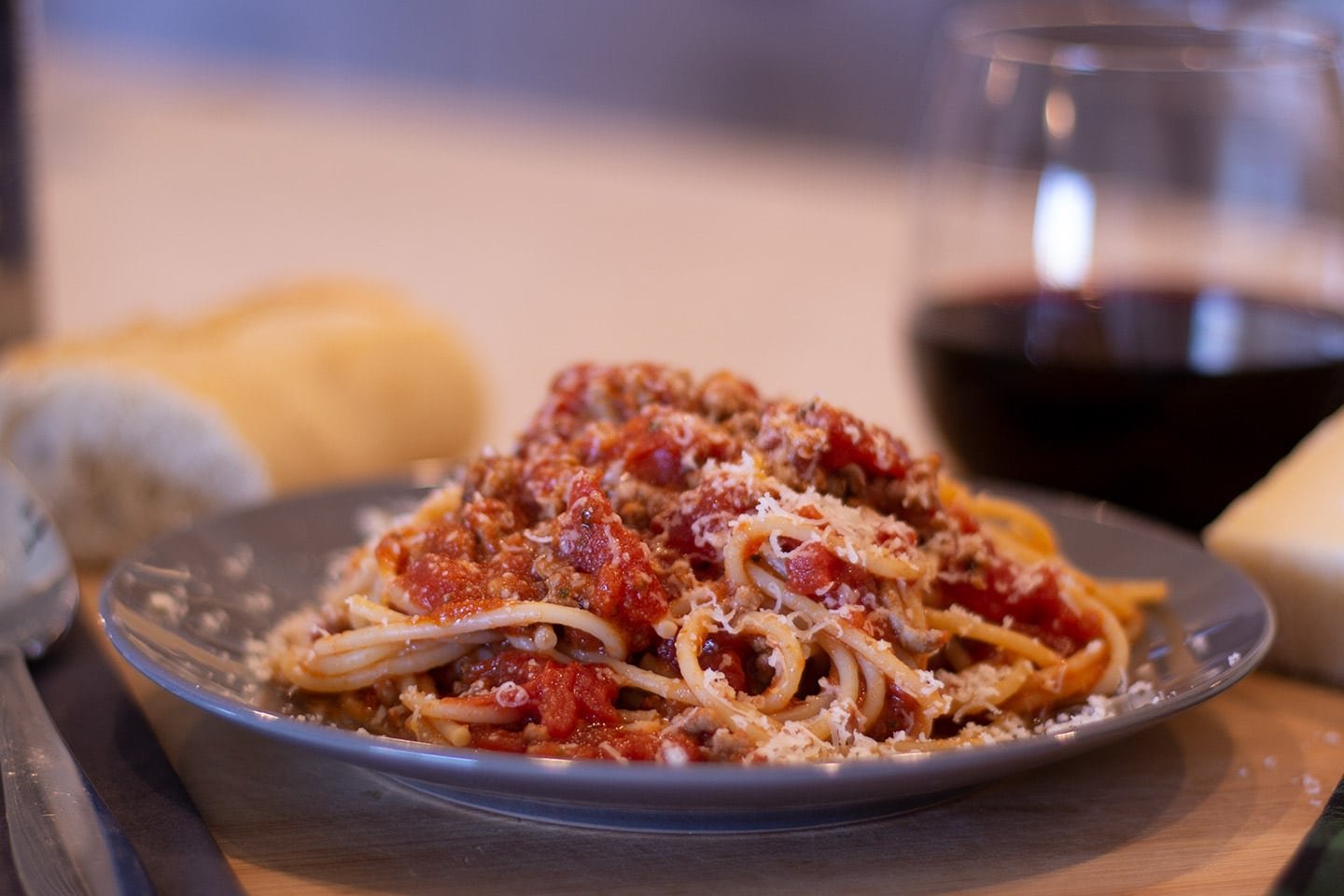 Spaghetti and meat sauce on a plate with a glass of wine