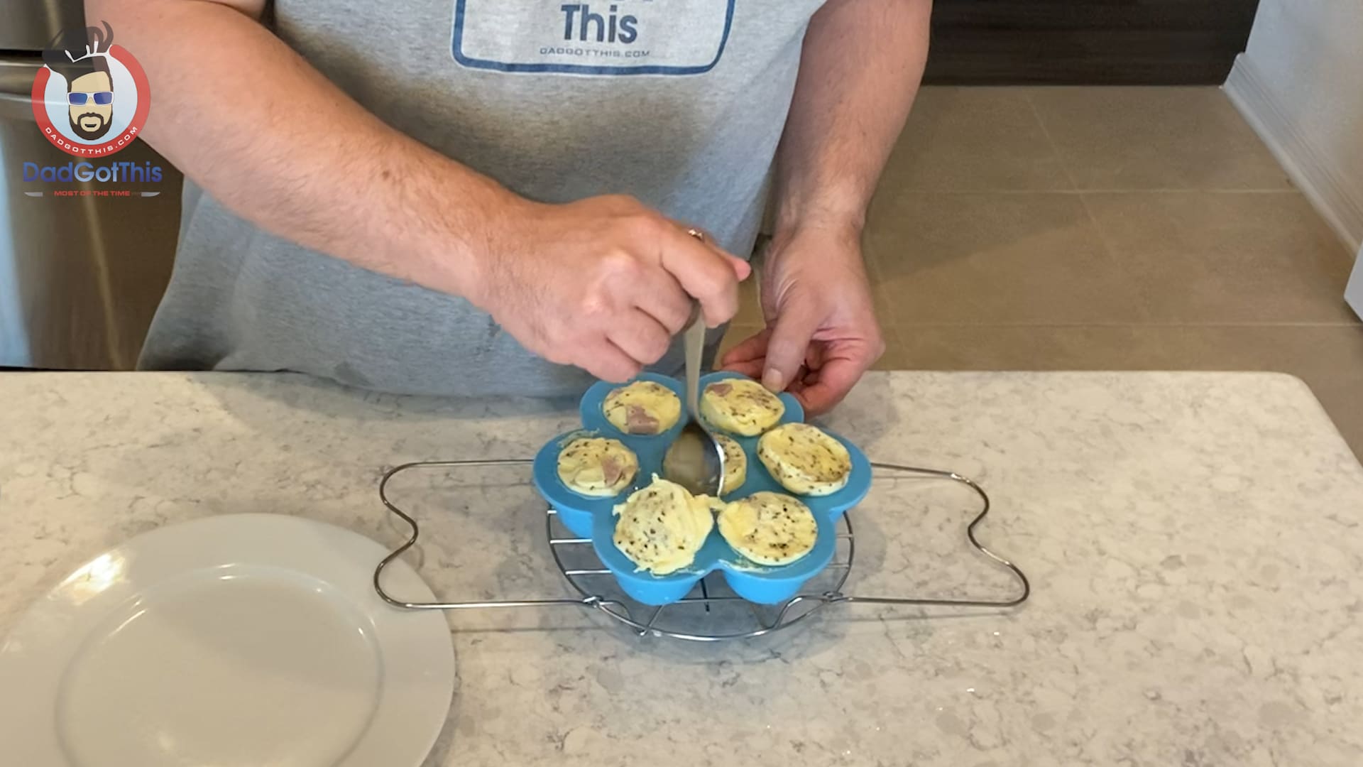 Running a spoon around the egg mold to release the egg bites