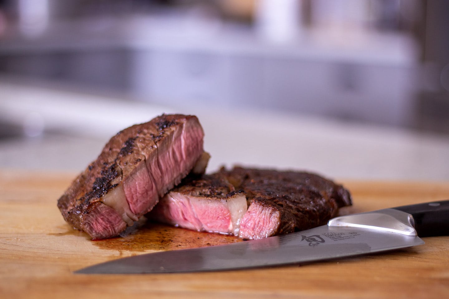 A cut ribeye steak with a knife on a cutting board