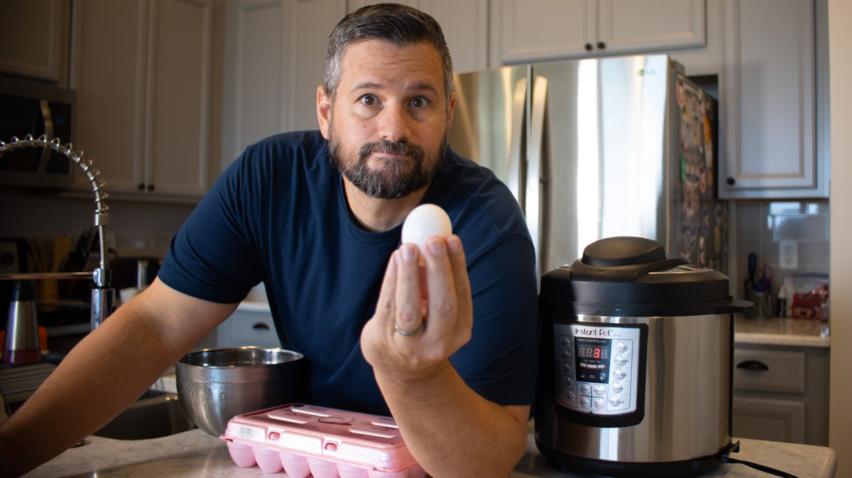 Dad holding an egg in front of an Instant Pot
