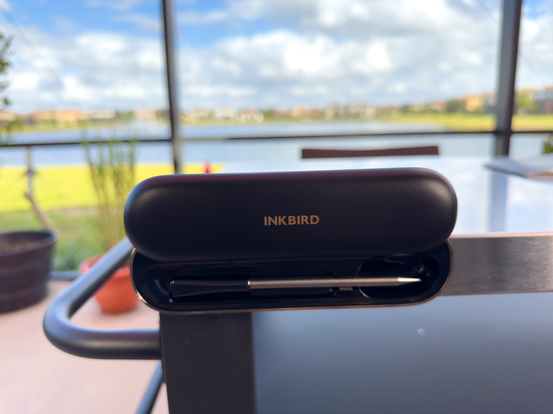 The INKBIRD INT-11P-B Wireless Thermometer probe inside its charging case magnetically attached to a BBQ cart.