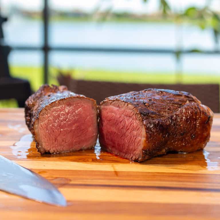 Smoked Picanha Steak on a cutting board with Ninja Woodfire in the background.