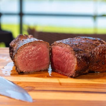 Smoked Picanha Steak on a cutting board with Ninja Woodfire in the background.