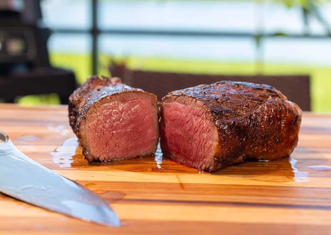 Smoked Picanha Steak on a cutting board with Ninja Woodfire in the background.