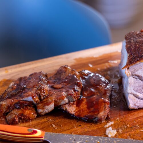 Sliced Filipino BBQ style pork glazed with banana ketchup sauce beside a smoked pork roast